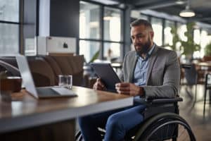 Auf dem Bild ist ein Rollstuhlfahrer zu sehen, wie er ein Tablet in der Hand hält. Es soll verdeutlichen, wie wichtig es ist, dass wir an alle unsere Mitbürger denken. Ganz egal ob Farbenblind, Blind, Bewegungseingeschränkt oder andere Handycaps.